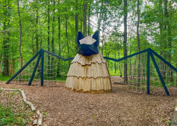 Afbeelding van een landmark sculptuur in de vorm van een vleermuis met verschillende touwen en klimrekken geïntegreerd in de vleugels.